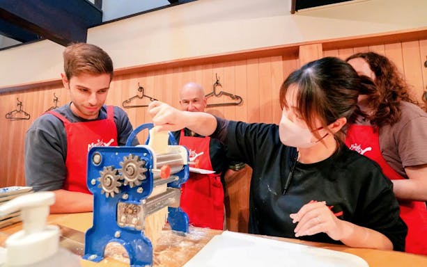 Participants making noodles in a Kyoto ramen and gyoza cooking class.