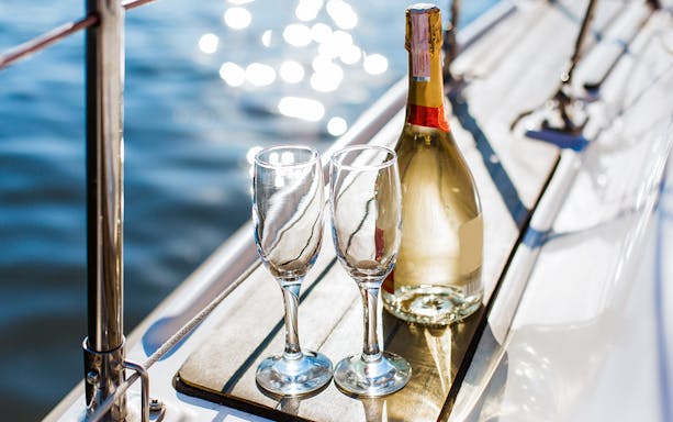 Champagne bottle and glasses on a boat deck during Syracuse tour.