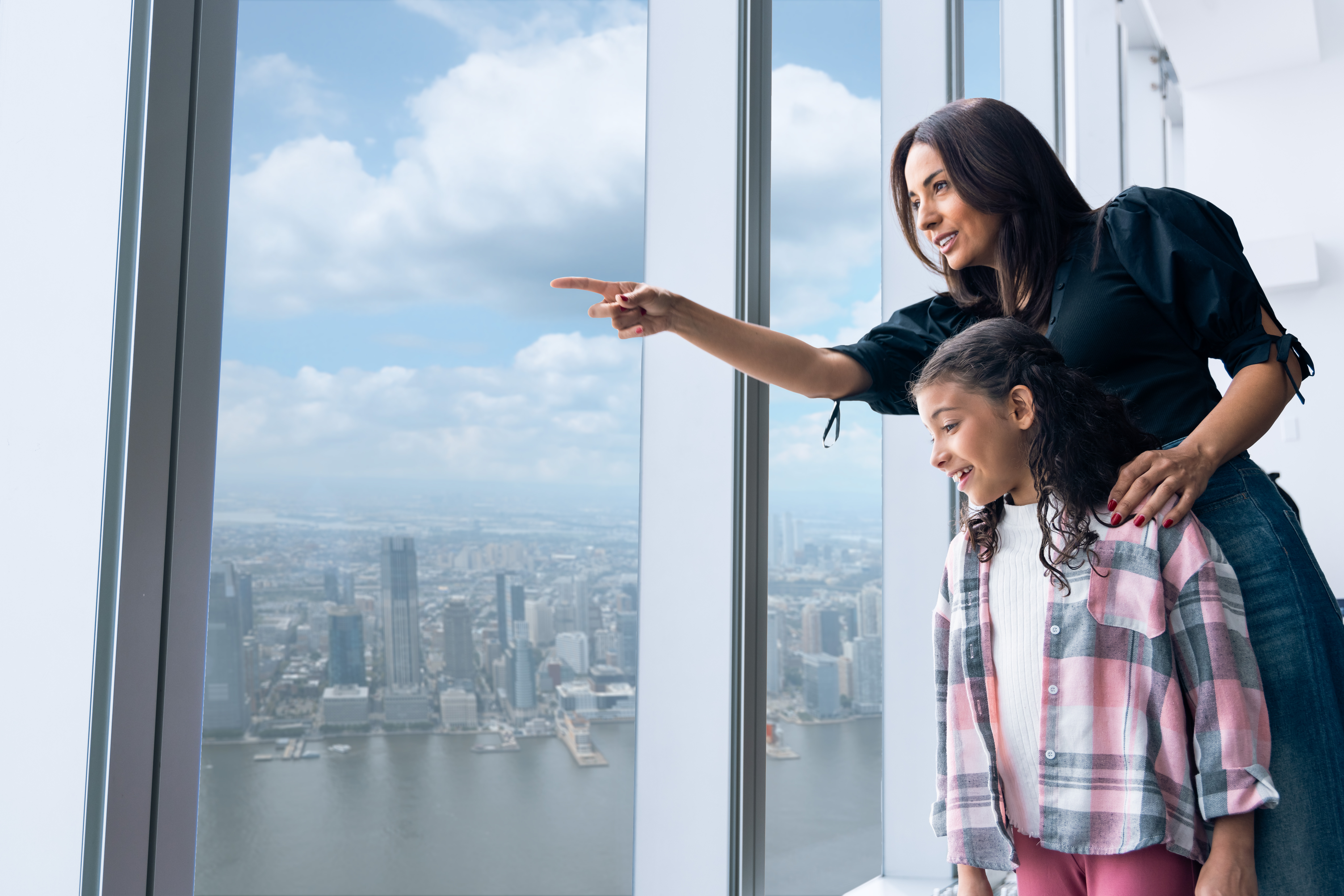 Visitors enjoying the view from One World Observatory, overlooking New York City skyline.