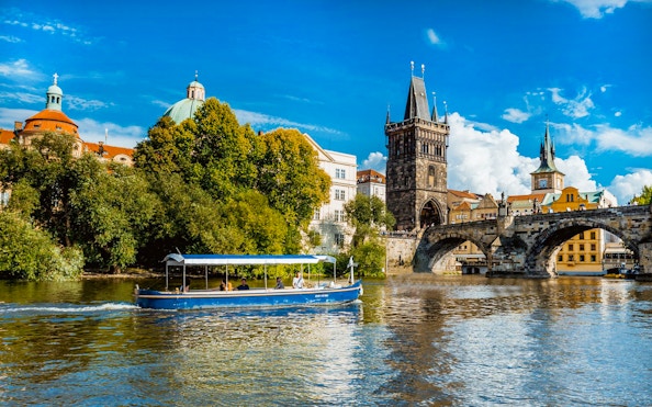 Sightseeing cruise boat on Vltava River near Charles Bridge, Prague.