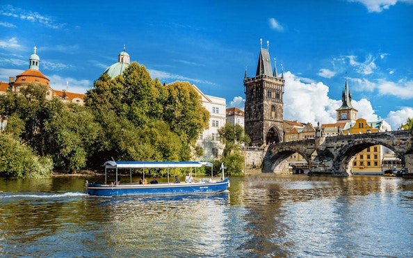 Sightseeing cruise boat on Vltava River near Charles Bridge, Prague.