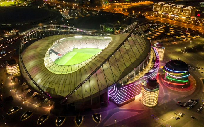 Khalifa International Stadium illuminated at night near Qatar Olympic And Sports Museum, Doha.