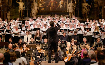 Orchestra and choir performing inside St. Stephen's Cathedral, Vienna, with audience seated.