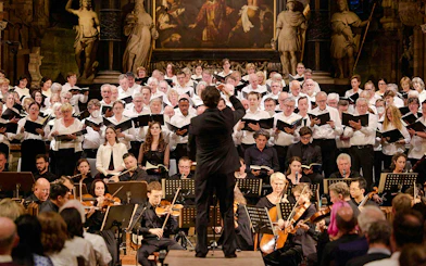 Orchestra and choir performing inside St. Stephen's Cathedral, Vienna, with audience seated.