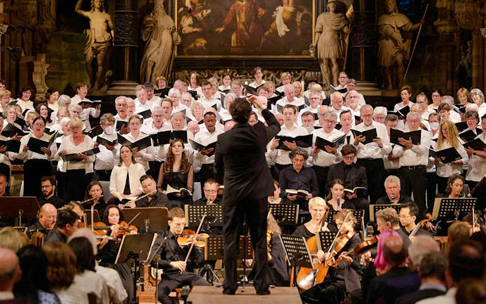 Orchestra and choir performing inside St. Stephen's Cathedral, Vienna, with audience seated.