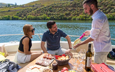 Tourists enjoying wine and snacks on a boat in Douro Valley, Portugal.