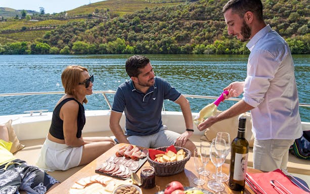 Tourists enjoying wine and snacks on a boat in Douro Valley, Portugal.