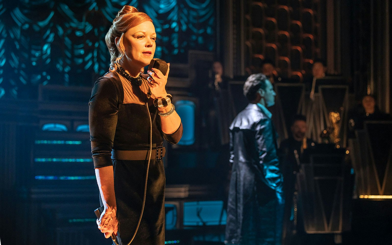 Performer on stage with microphone during a theatrical show.