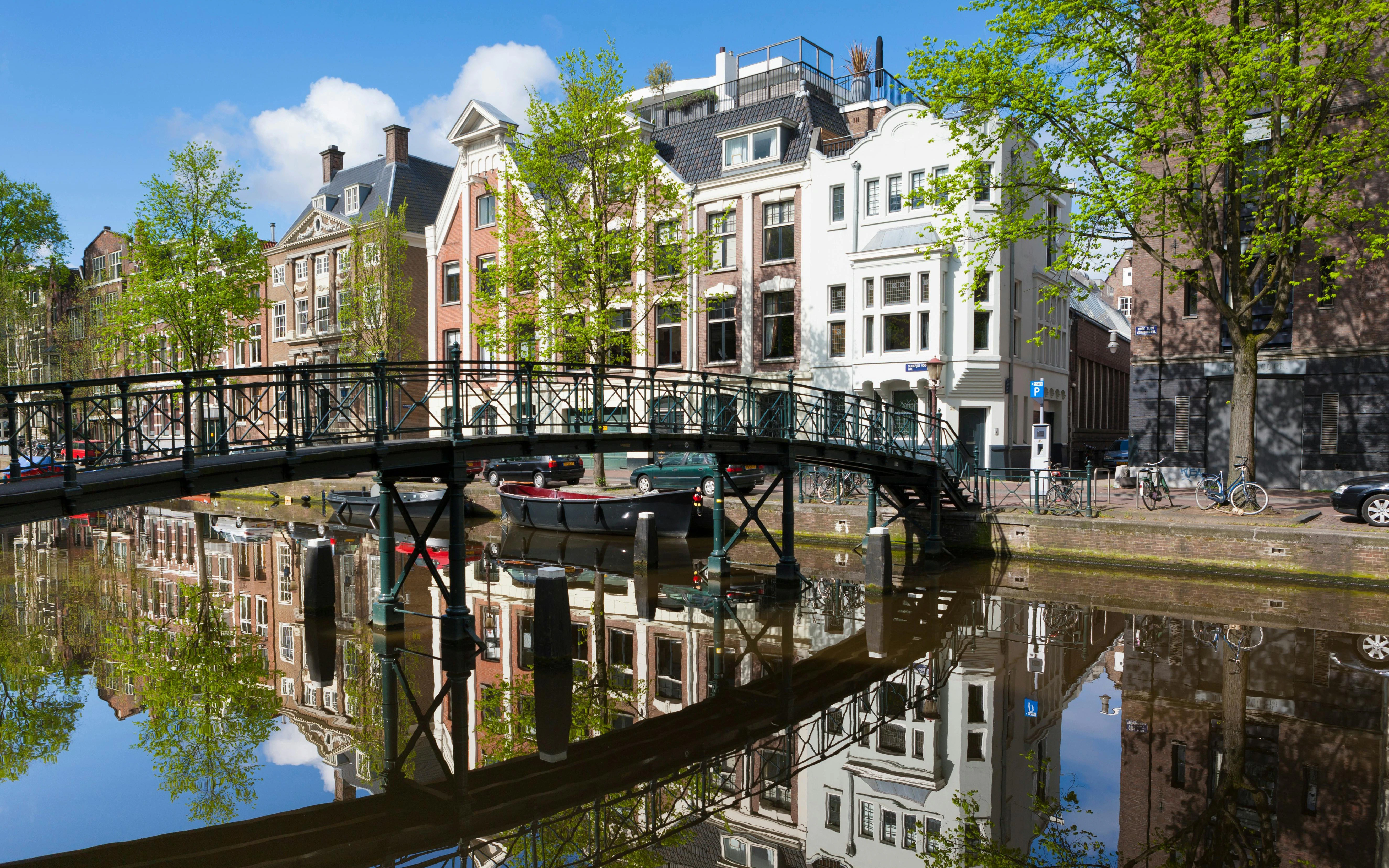 Alte Grachtenhäuser spiegeln sich im Wasser am Oudezijds Voorburgwal, Amsterdam, Niederlande.