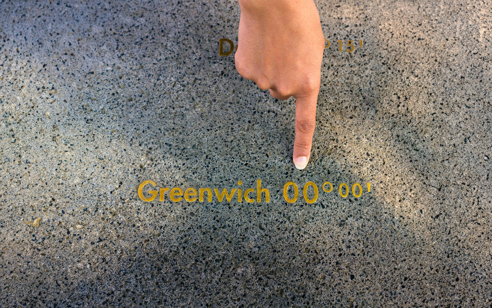 Finger pointing at the Prime Meridian line at Royal Observatory Greenwich.