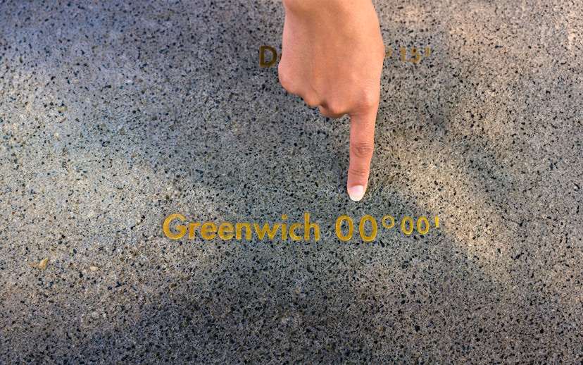 Finger pointing at the Prime Meridian line at Royal Observatory Greenwich.