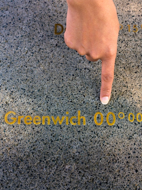 Finger pointing at the Prime Meridian line at Royal Observatory Greenwich.