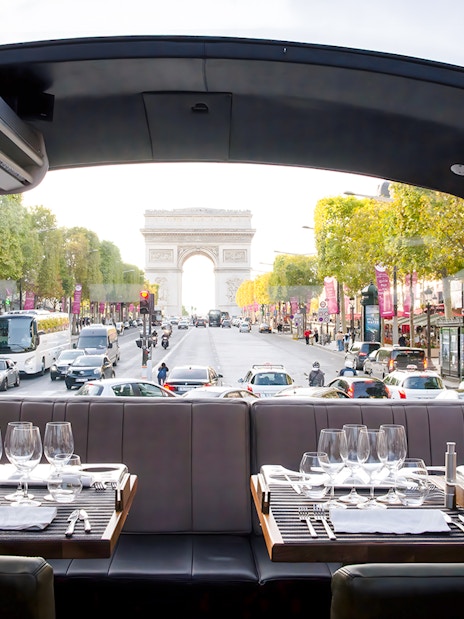 Dining setup inside Bustronome Paris with view of Arc de Triomphe.