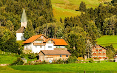 Bavarian village with traditional houses and church surrounded by lush greenery.