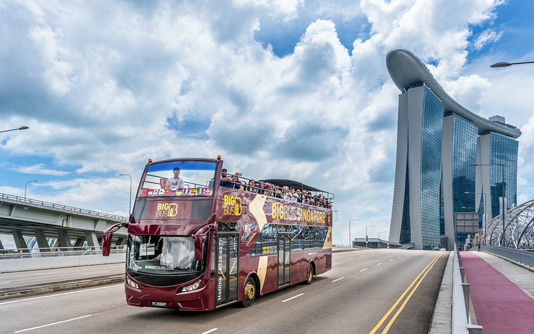 Big Bus tour near Marina Bay Sands, Singapore with passengers on top deck.