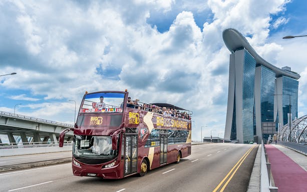 Big Bus tour near Marina Bay Sands, Singapore with passengers on top deck.