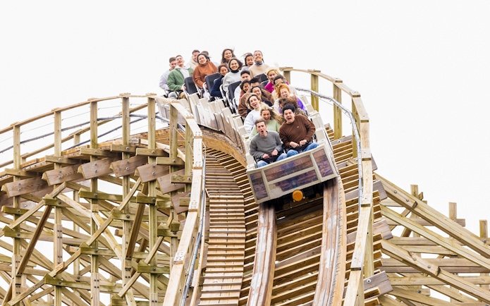 Riders on Coaster Express at Parque Warner Madrid descending a wooden track.