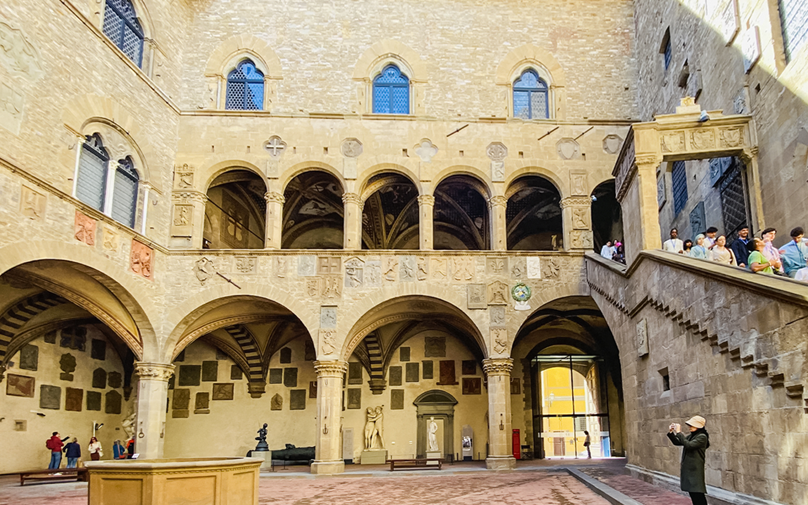 Bargello Museum courtyard with tourists on staircase, Florence, Italy.