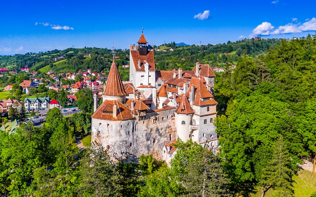 Bran Castle in Romania with iconic towers and medieval architecture surrounded by lush greenery.