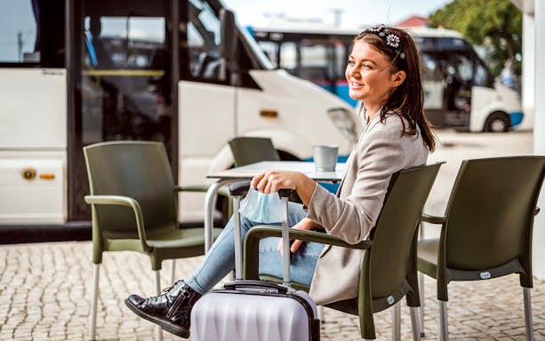 Traveler waiting with luggage for private Faro airport minibus transfer.