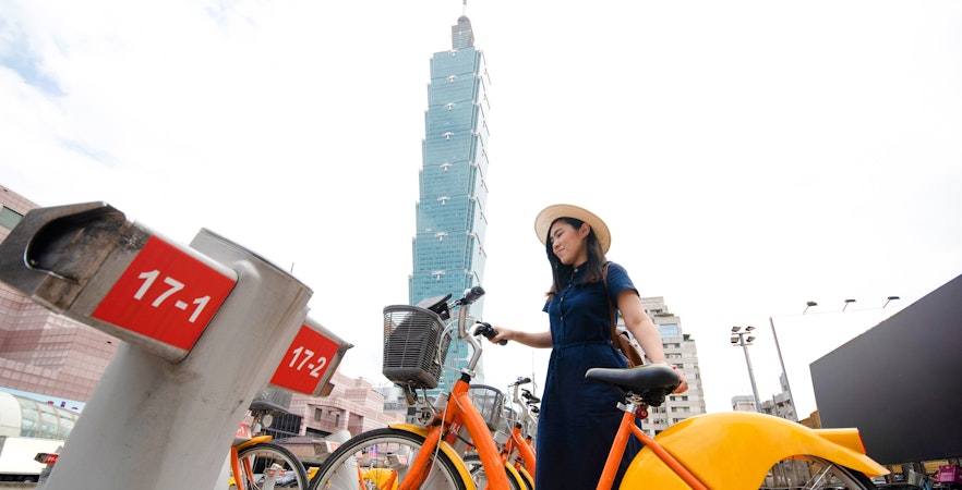 Woman renting bicycle near Taipei 101 in Taipei, Taiwan.