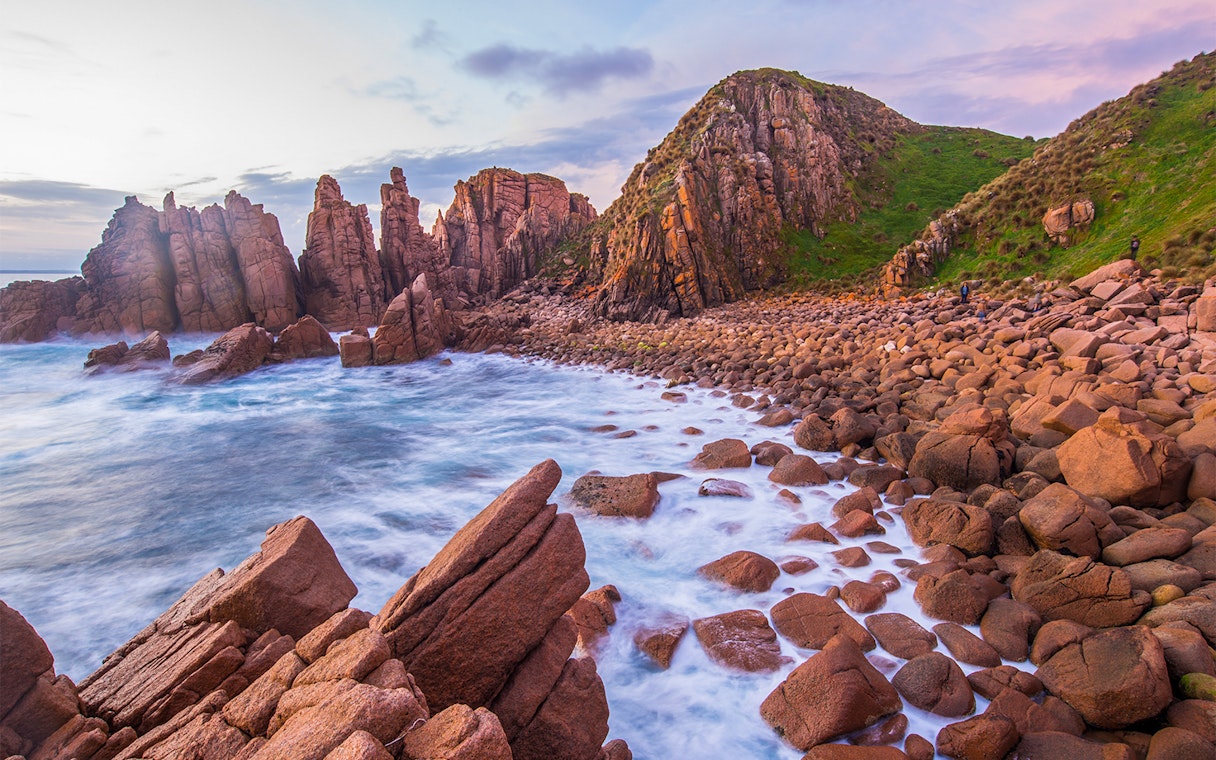 Rocky coastline and ocean waves at sunset on Churchill Island, Australia.