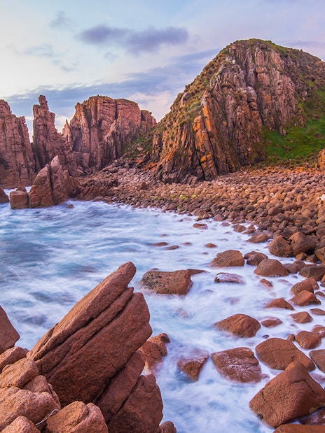 Rocky coastline and ocean waves at sunset on Churchill Island, Australia.
