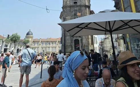 People enjoying a sunny day at an outdoor café near Clérigos Tower, Porto.