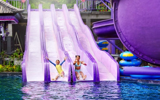 Children sliding down water slides at Toya Devasya Hot Spring Water Park, Bali.