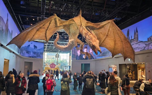 Dragon exhibit at Harry Potter Studio Tour London with visitors exploring the attraction.