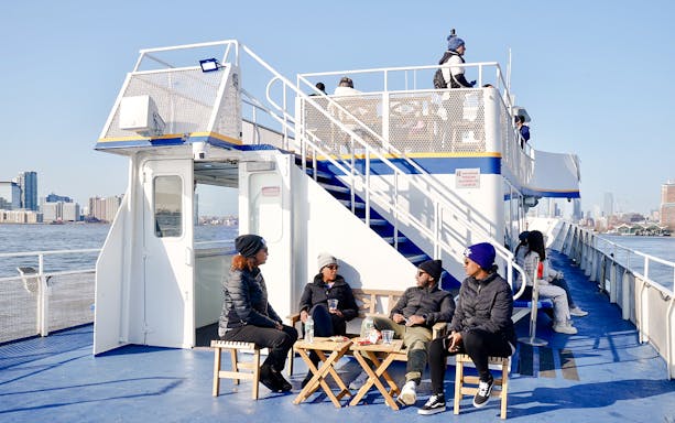 Guests relaxing on a sightseeing cruise with views of New York City skyline.