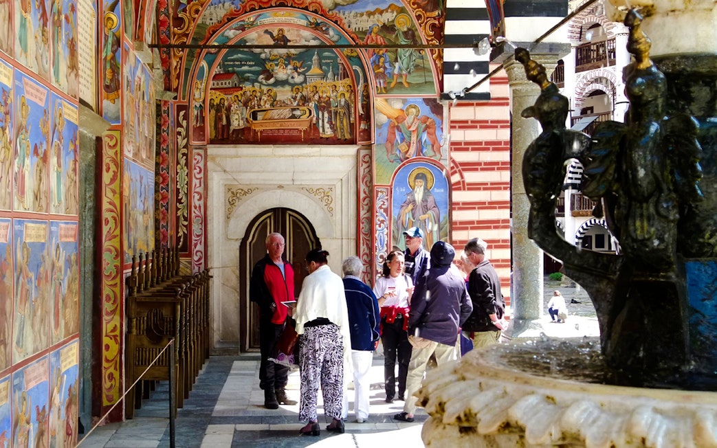 Guide and tourists near frescoes inside Rila Monastery, Bulgaria.