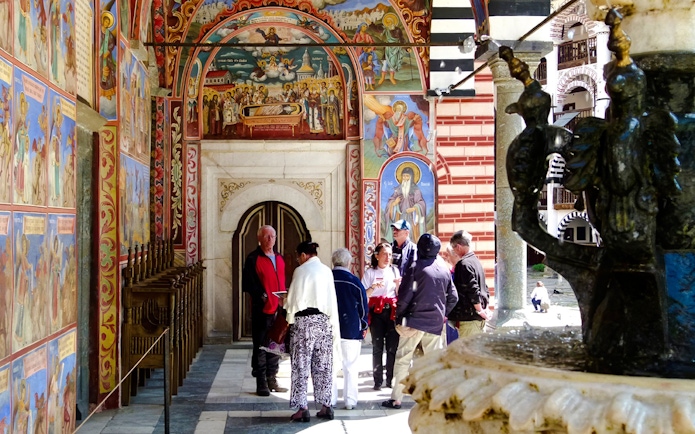 Guide and tourists near frescoes inside Rila Monastery, Bulgaria.