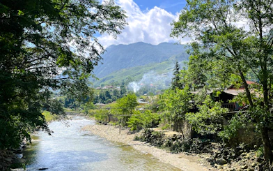 River and village landscape in Lao Chai, Sapa, with mountains in the background.