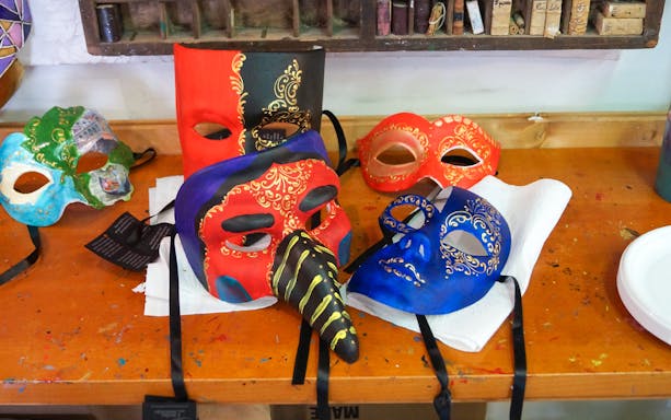 Venetian masks on a table during a glass and mask-making tour in Venice.