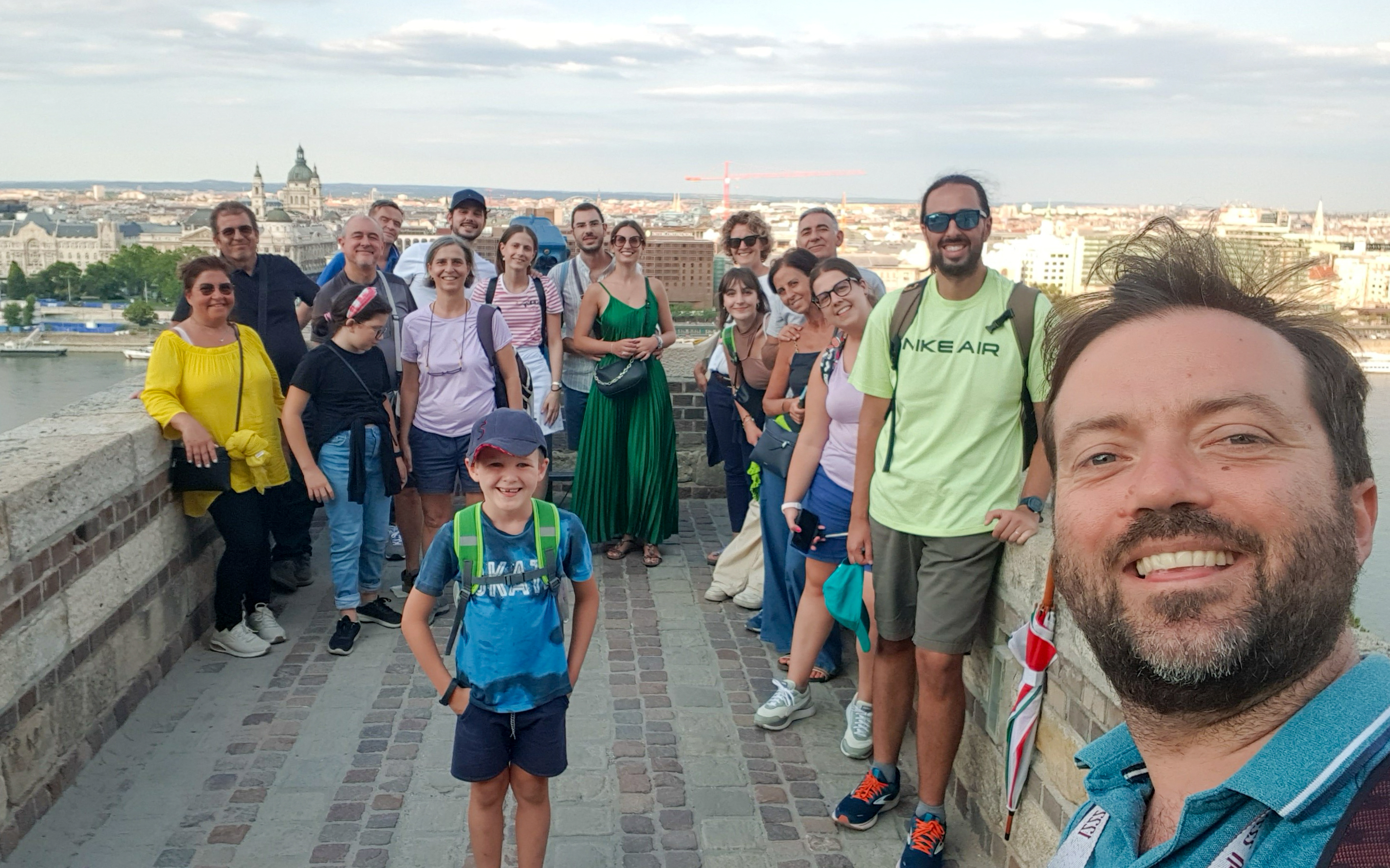 Group of tourists with guide on Buda tour, Budapest skyline in background.