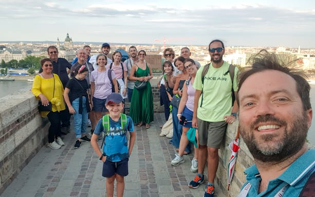 Group of tourists with guide on Buda tour, Budapest skyline in background.