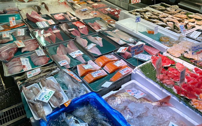 Fresh seafood display at Tsukiji Market, Tokyo, featuring various fish and sashimi cuts.