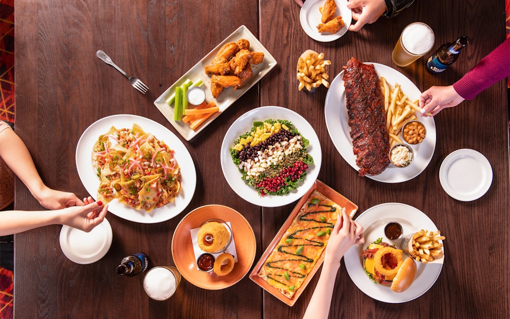 Hard Rock Cafe Milan table with nachos, salad, ribs, wings, and burger.