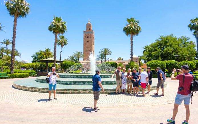 Tourists at a fountain with Koutoubia Mosque in Marrakech, Morocco.