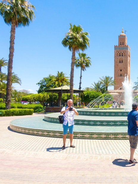 Tourists at a fountain with Koutoubia Mosque in Marrakech, Morocco.