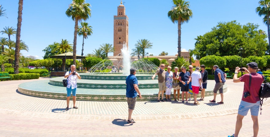 Tourists at a fountain with Koutoubia Mosque in Marrakech, Morocco.
