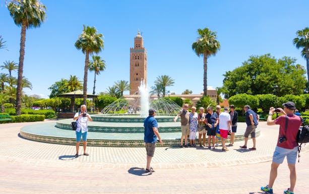 Tourists at a fountain with Koutoubia Mosque in Marrakech, Morocco.