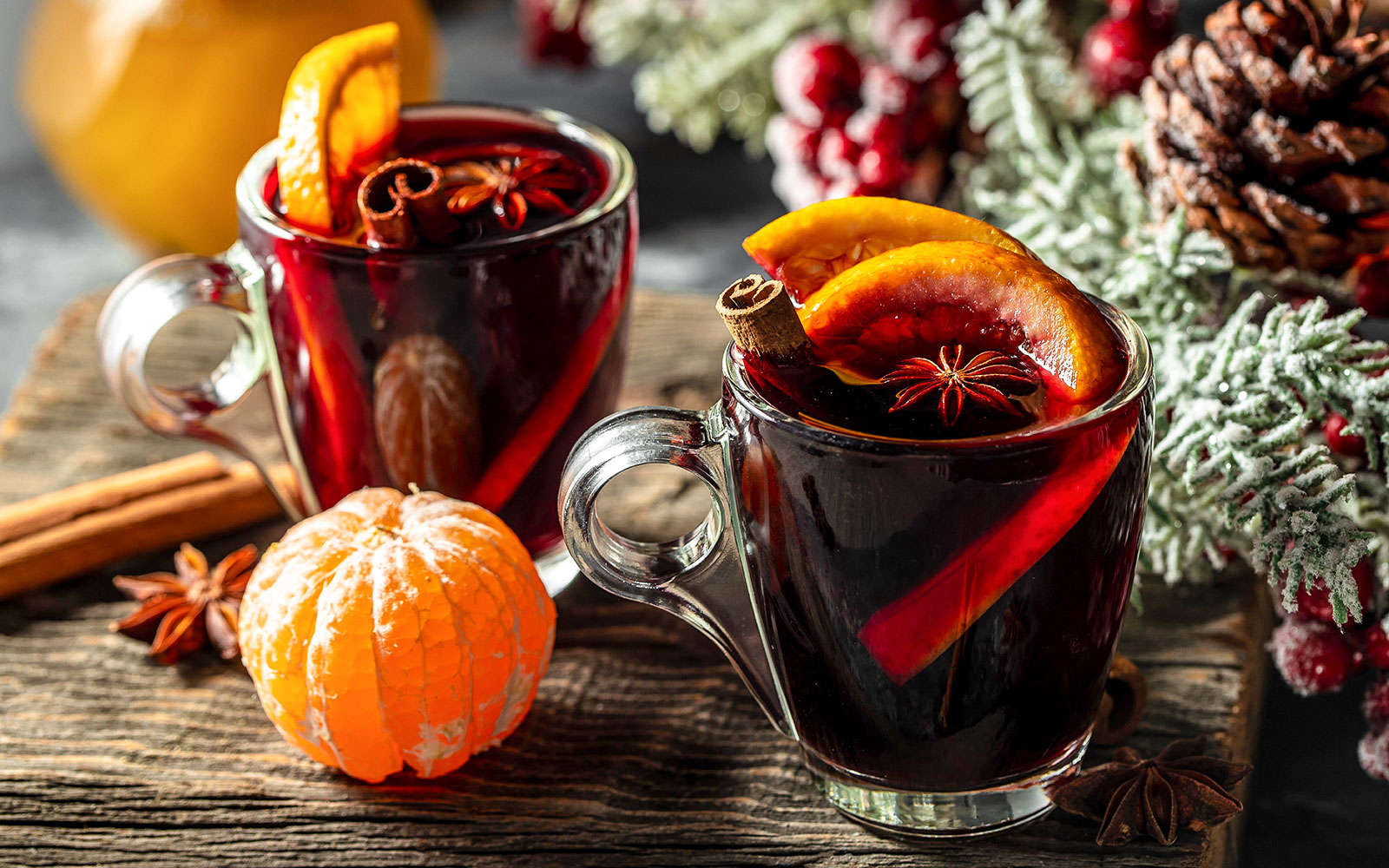 Mulled wine with orange slices and spices on a wooden table, winter setting.