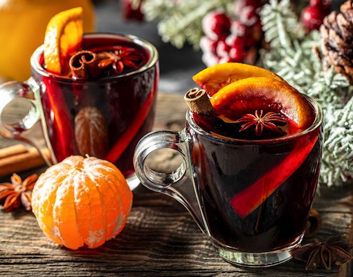 Mulled wine with orange slices and spices on a wooden table, winter setting.