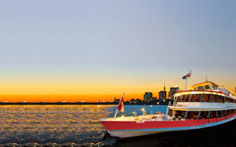 Cruise ship on the Danube River at sunset with city skyline in the background.