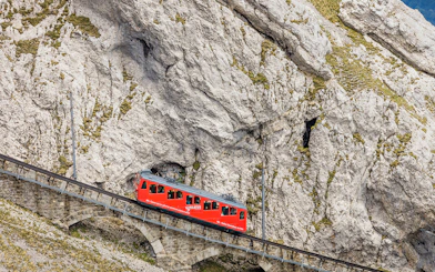 Red cogwheel train ascending Mount Pilatus in Lucerne, part of the Swiss Travel System.