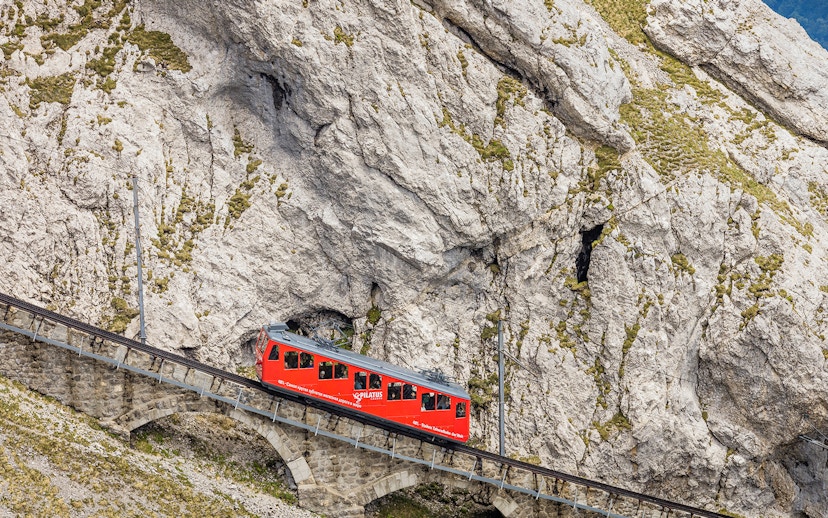 Red cogwheel train ascending Mount Pilatus in Lucerne, part of the Swiss Travel System.