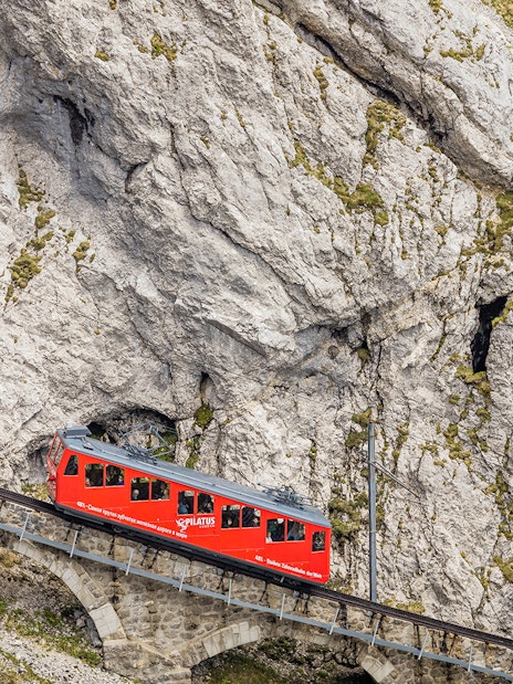 Red cogwheel train ascending Mount Pilatus in Lucerne, part of the Swiss Travel System.