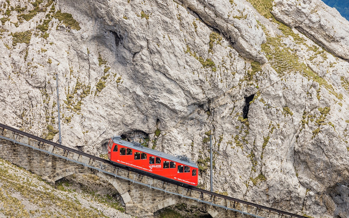 Red cogwheel train ascending Mount Pilatus in Lucerne, part of the Swiss Travel System.